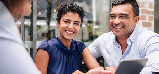 Three people sitting at a table smiling at each other
